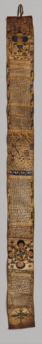 Rollo etíope largo y estrecho de pergamino, cubierto de escritura en ge'ez y paneles con rostros, ojos, cruces y figuras protectoras.