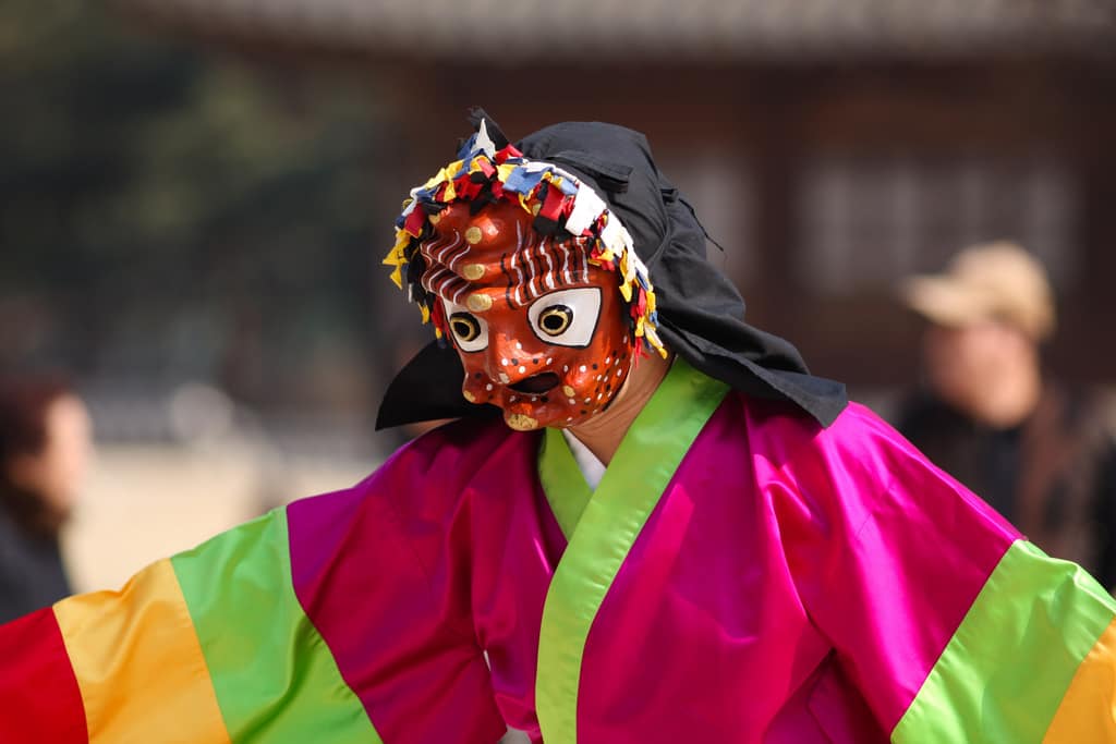 Bailarín de talchum coreano con máscara, sombrero y vestuario tradicional.