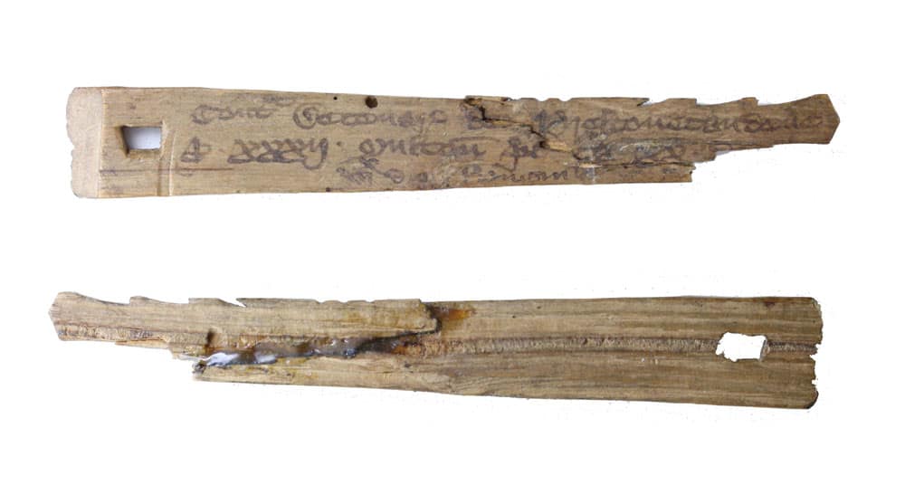 Dos tally sticks medievales de madera, con inscripciones y cortes de registro visibles.