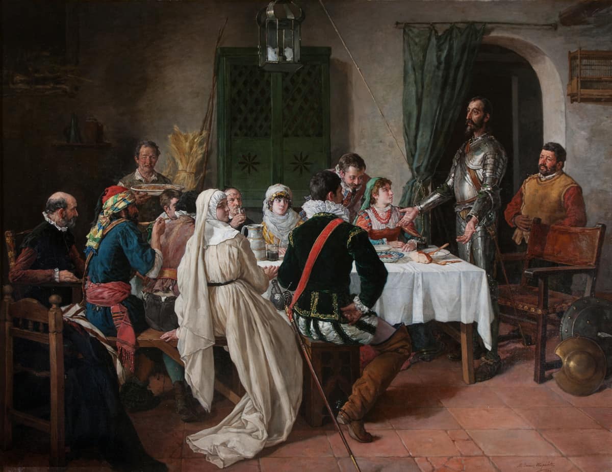 Don Quijote habla de pie ante varias personas sentadas alrededor de una mesa en la venta.