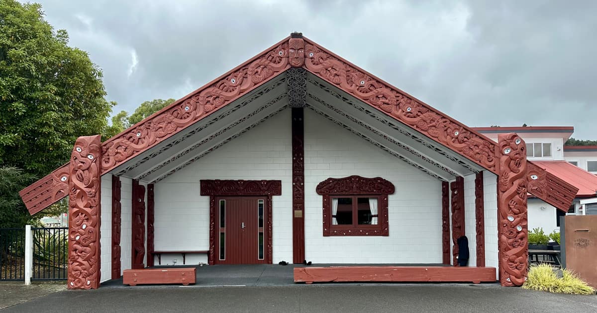 Fachada tallada del wharenui del Ōrongomai Marae bajo un cielo nublado.