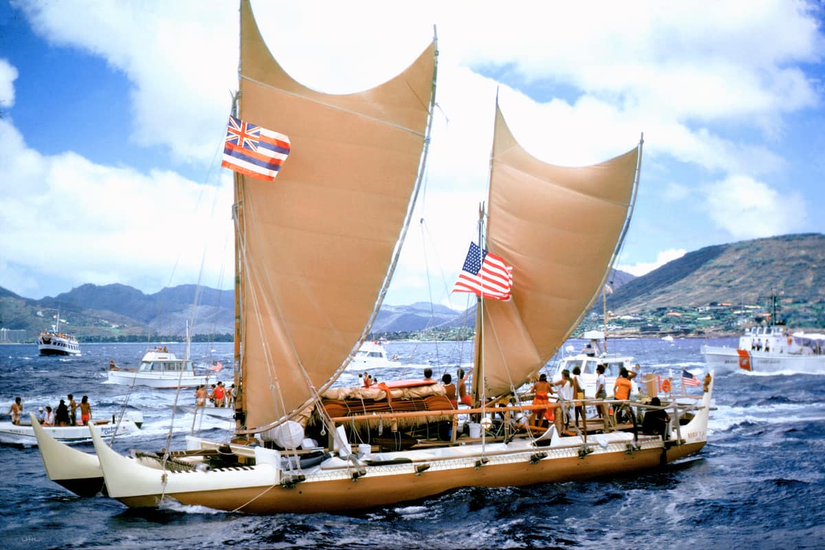 Canoa de doble casco Hōkūleʻa navegando con sus velas durante la llegada de 1976.