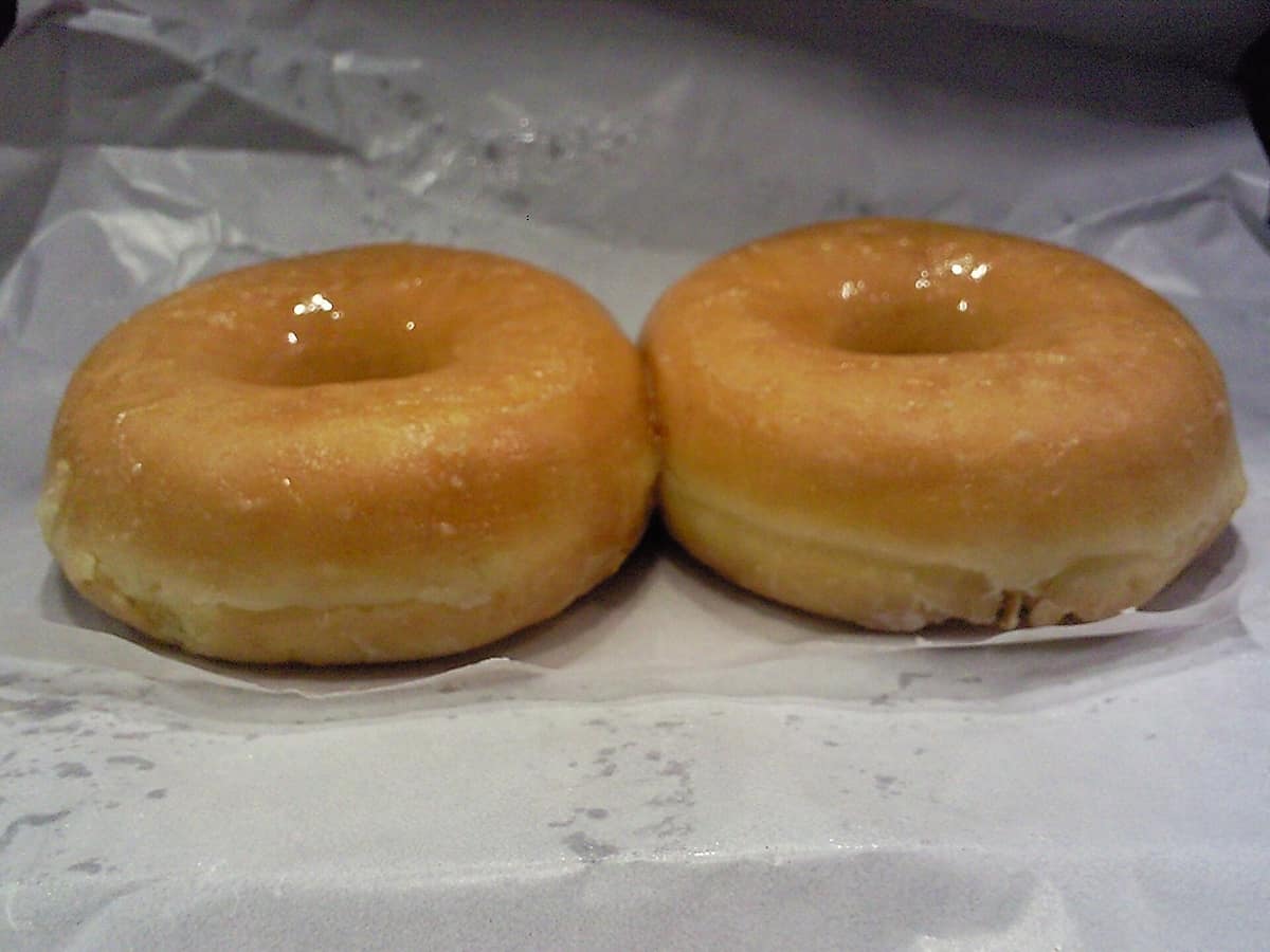Doughnut de masa frita con forma de anillo y un hueco central visible.