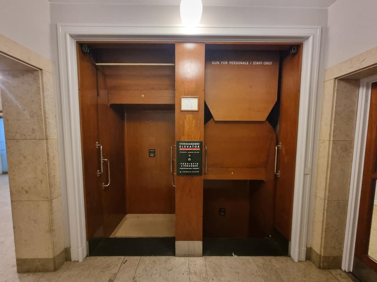 Dos accesos abiertos de un ascensor paternoster dentro de un edificio público.