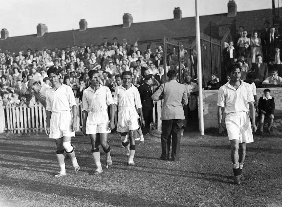 La selección india entra en el campo para jugar contra Francia en 1948; varios futbolistas caminan descalzos.