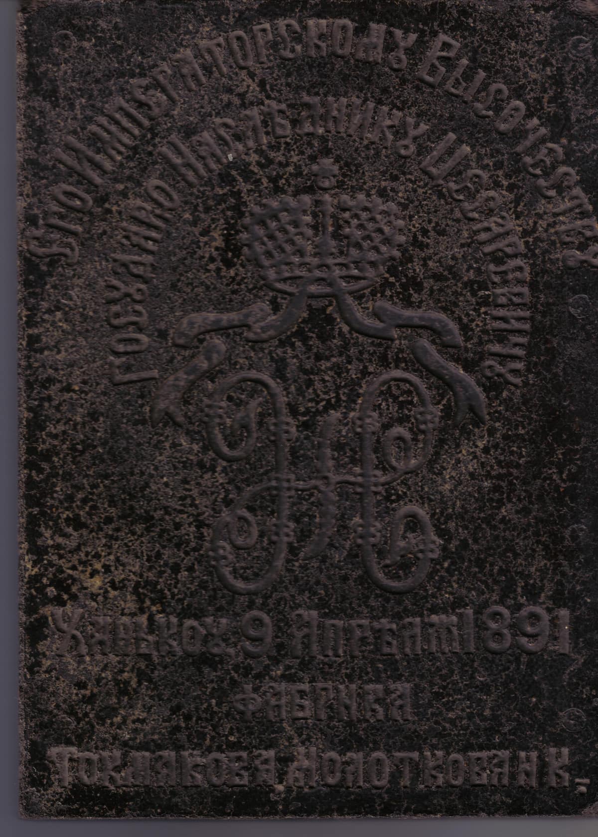 Ladrillo rectangular de té prensado, oscuro y ornamentado, con relieves decorativos y una inscripción en caracteres cirílicos.