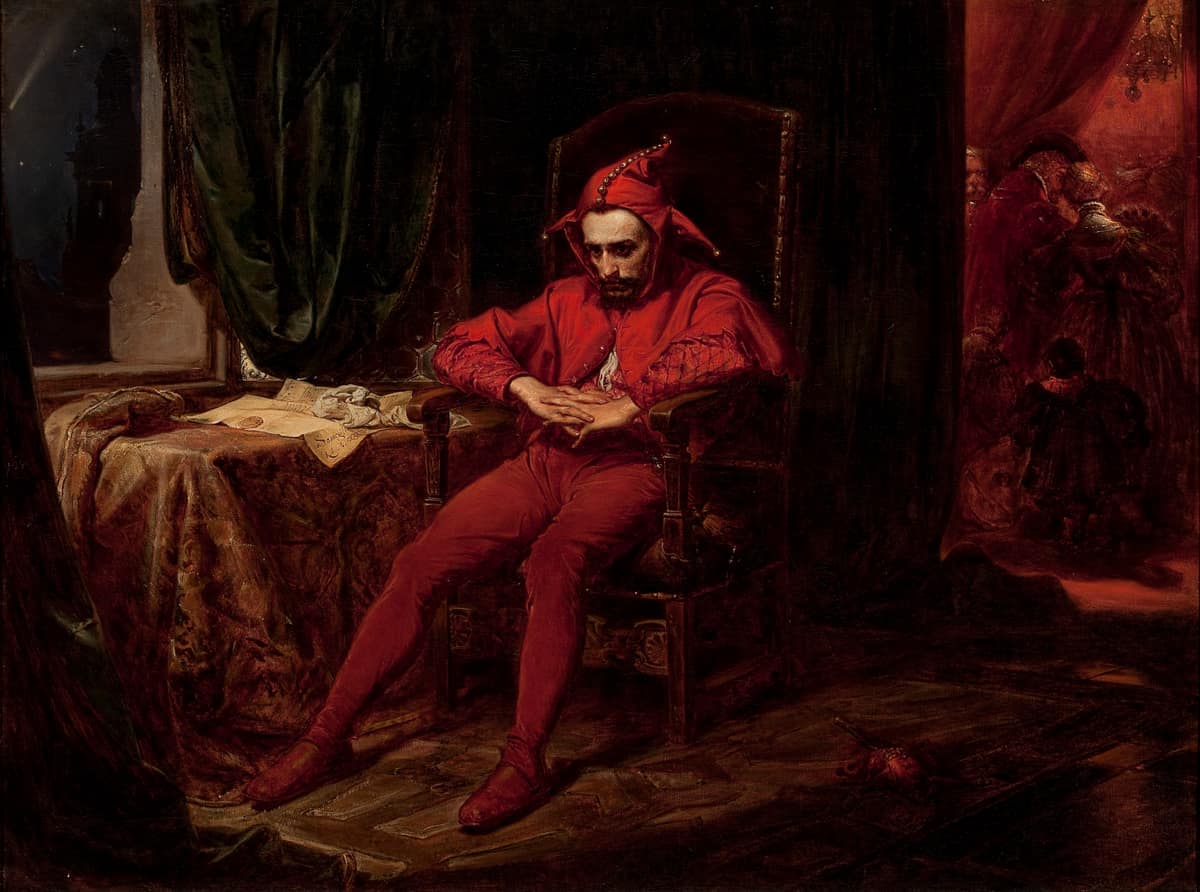 Stańczyk vestido de rojo, sentado y pensativo ante una mesa mientras un baile cortesano continúa al fondo.