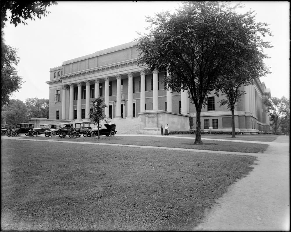 Fachada de Widener Library en Harvard en agosto de 1920, con automóviles y un cañón conmemorativo en el exterior.