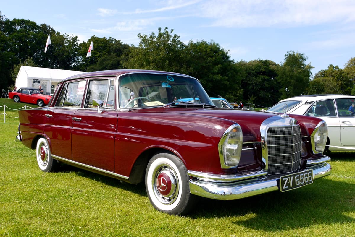 Mercedes-Benz 220S W111 de dos tonos estacionado sobre césped durante una exposición de automóviles clásicos en Terenure, Dublín.
