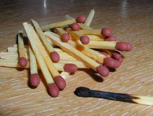 Fotografía de un montón de cerillas de madera con cabezas rojas.