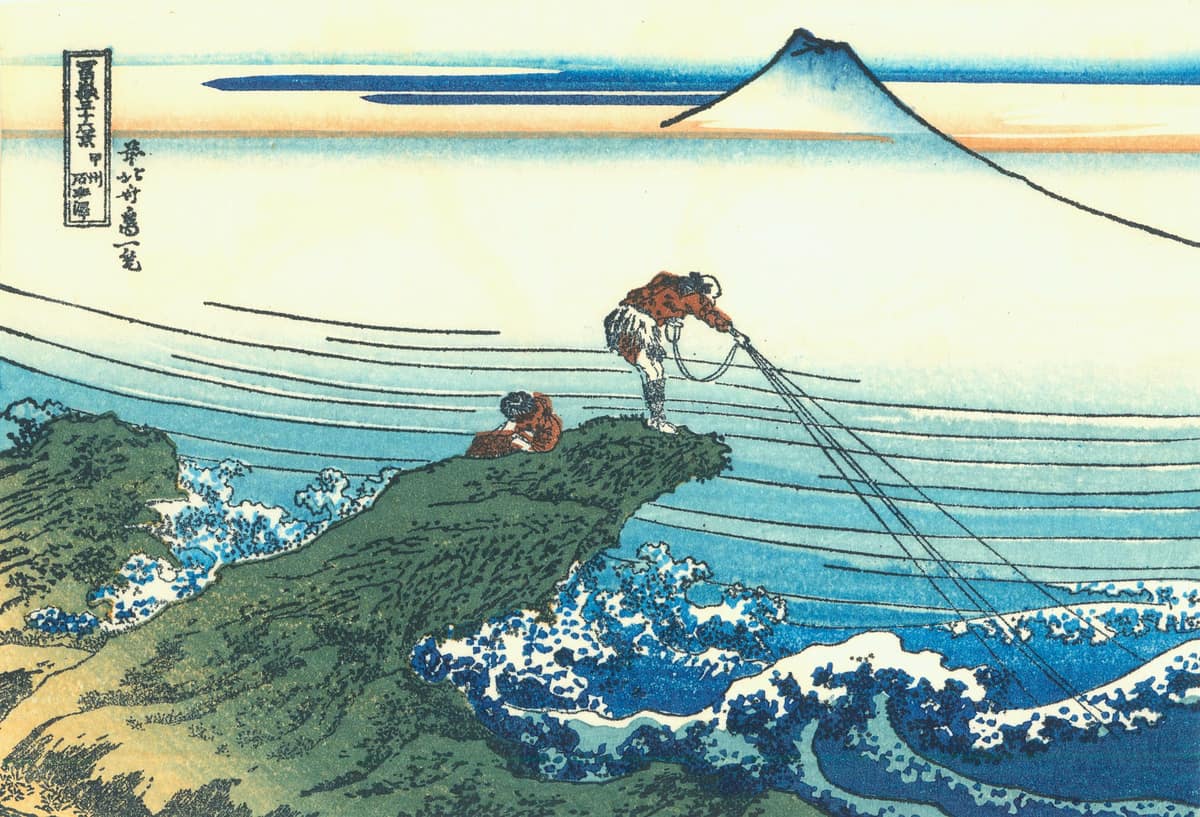 Estampa japonesa azul de Hokusai con un pescador sobre una roca y el monte Fuji al fondo.