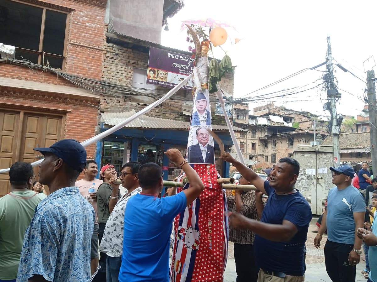Hombres de Bhaktapur transportan por la calle una estructura de bambú con retratos políticos durante Gai Jatra.