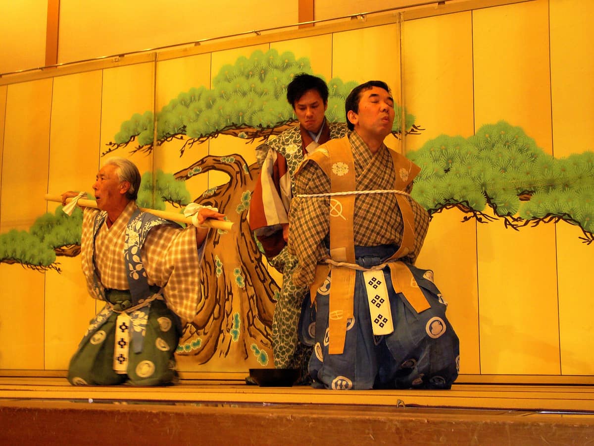 Dos actores de kyōgen interpretando una escena cómica en un escenario de Kioto.