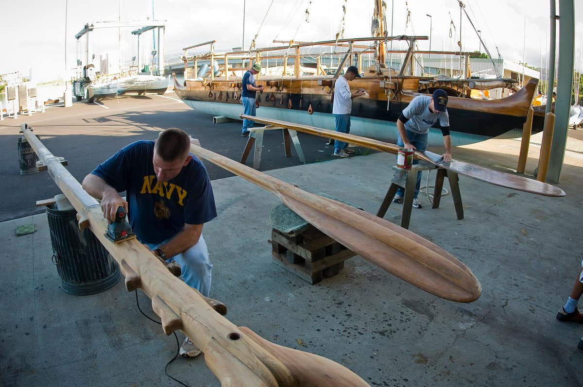 Marineros lijan piezas de la canoa Hōkūleʻa durante labores de restauración en Honolulu.